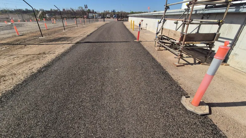Newly sealed access road alongside fuel tank farm bund wall