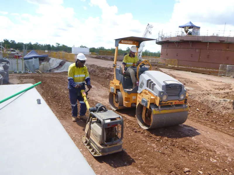 Roller and plate compactor crew working around a tank farm pad