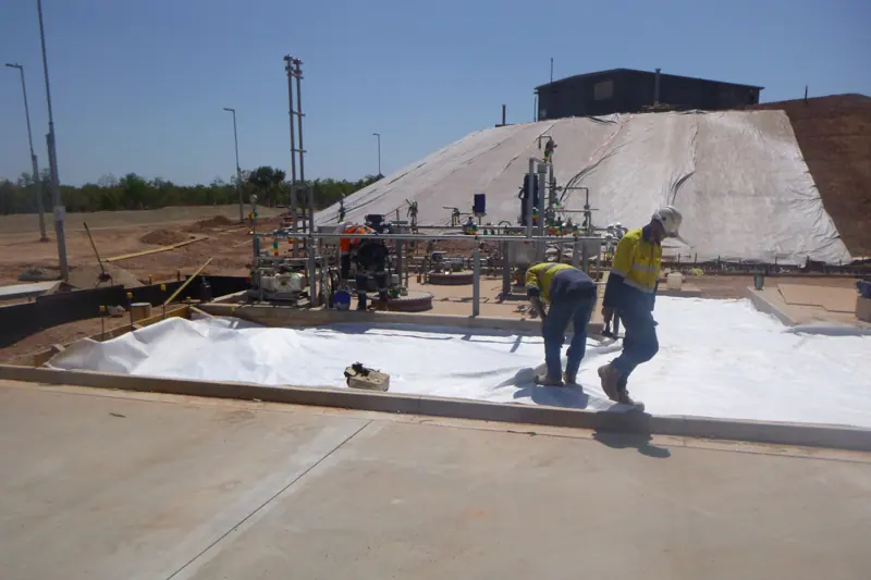 Crew laying geofabric within a concrete bund area
