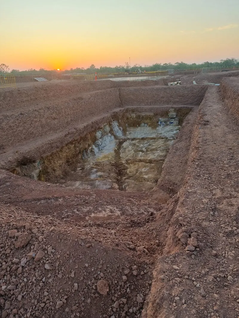 Deep benched bulk excavation into rock at sunset