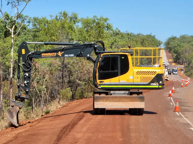 Wombarra wheeled excavator trimming a highway batter under traffic control
