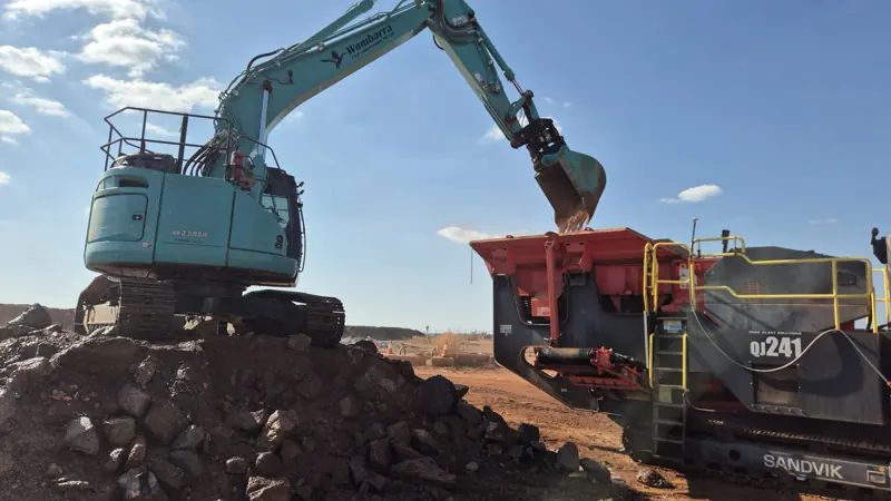 Wombarra excavator feeding a mobile jaw crusher with rock