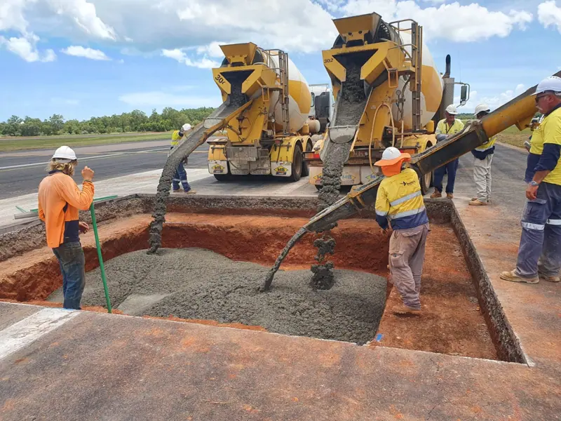 Concrete trucks pouring a large pavement section