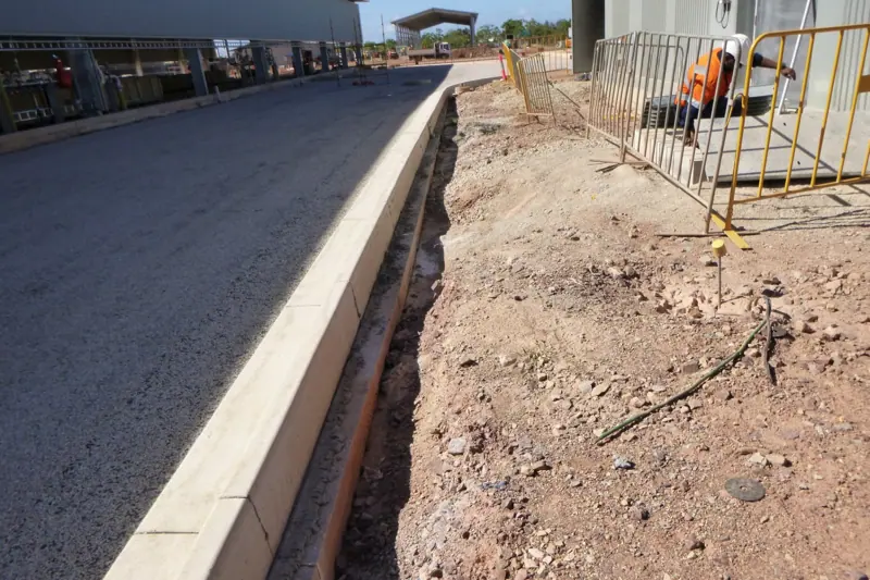 Narrow services trench running along a kerb line at a plant site