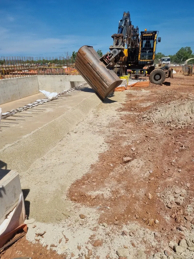 Wheeled excavator with compaction bucket working a concrete channel