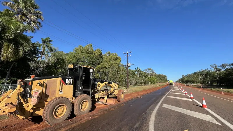 Two motor graders rebuilding a road shoulder under traffic control