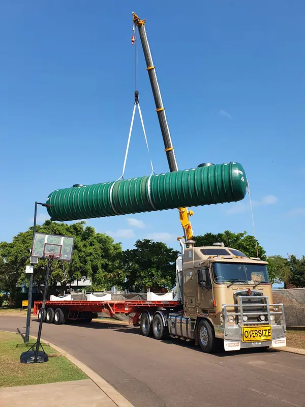 Crane truck lifting a large poly tank into position