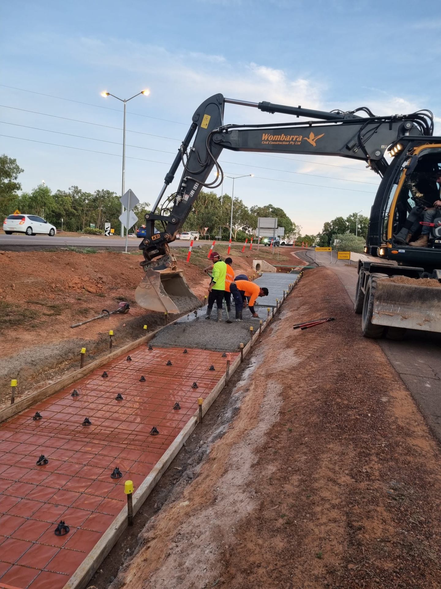 Wombarra-branded excavator placing concrete at Territory roundabout upgrade