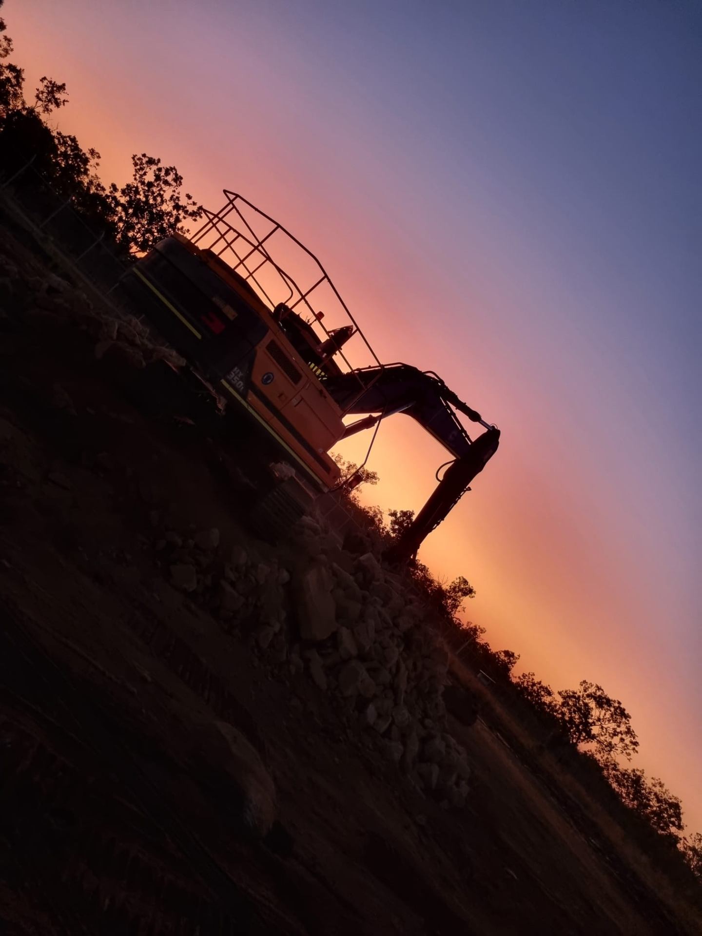 Wombarra excavator silhouetted against Territory sunset on rock excavation
