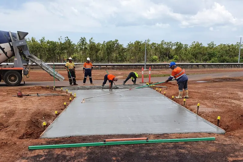 Crew finishing a concrete slab pour at a solar farm