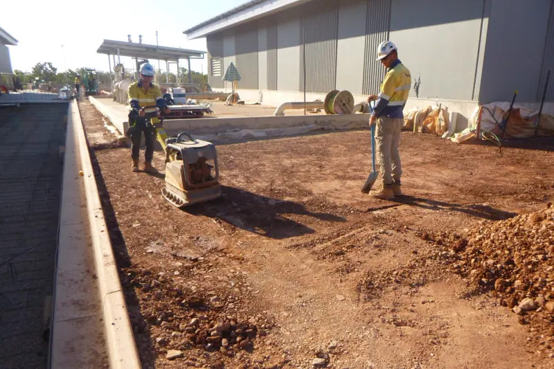 Compaction crew preparing subgrade alongside a new kerb line