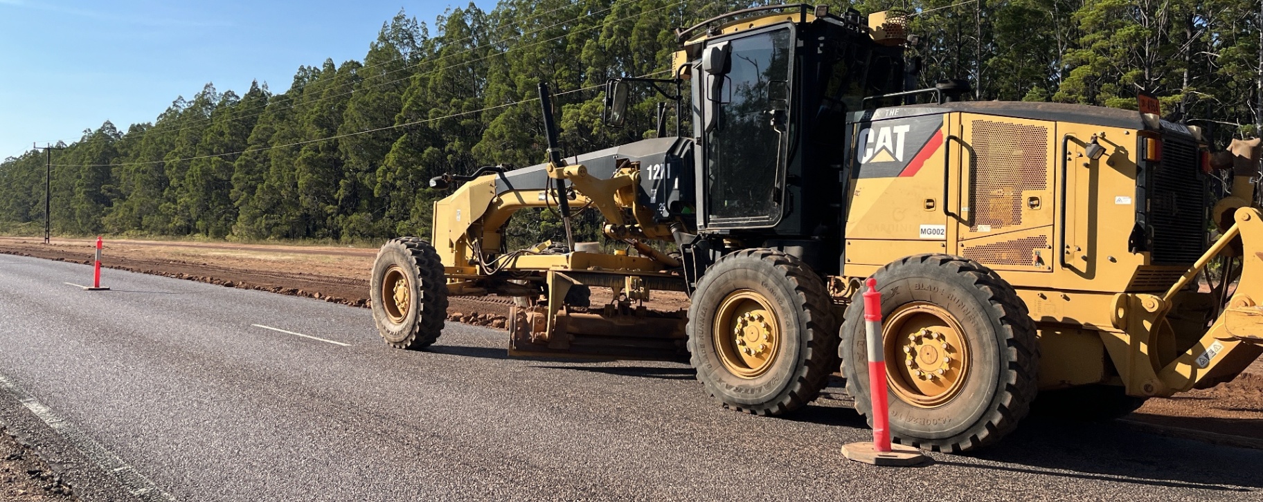 Motor grader trimming rural highway shoulder