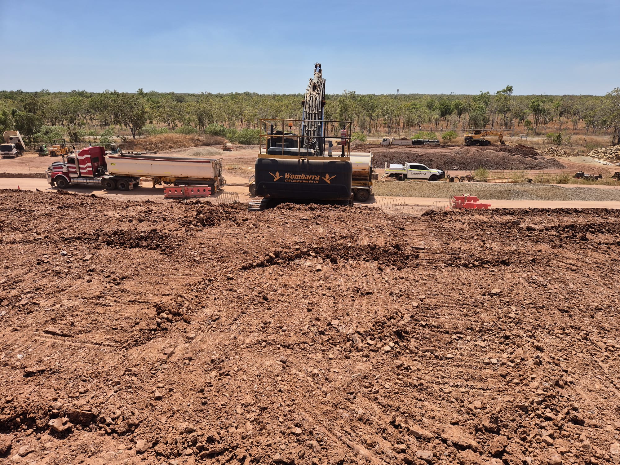 Wombarra branded excavator and side tipper on active Territory bulk earthworks site