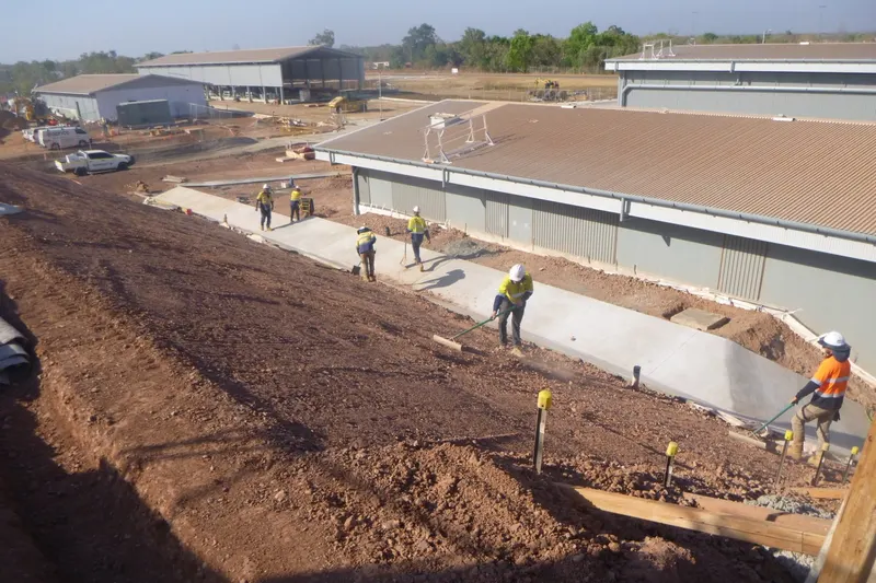 Crew trimming earthworks alongside a new concrete pathway